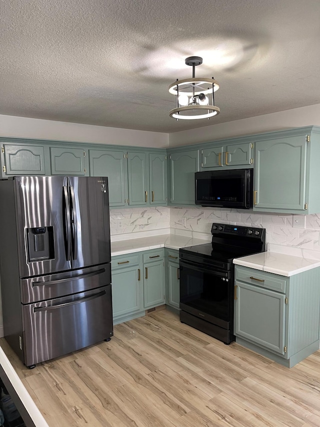 kitchen featuring green cabinetry, black appliances, light hardwood / wood-style floors, and tasteful backsplash