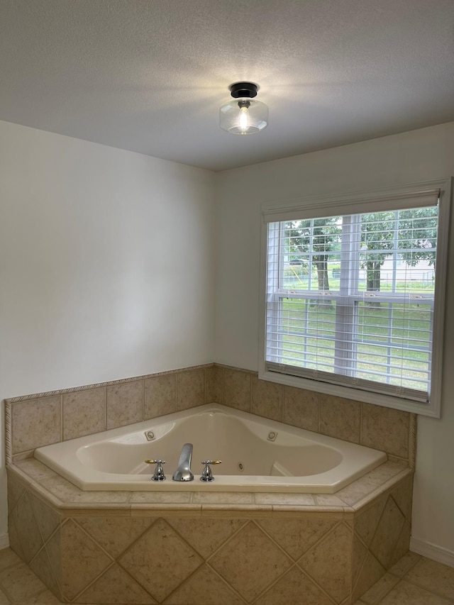 bathroom featuring tile patterned floors, a relaxing tiled tub, and a textured ceiling