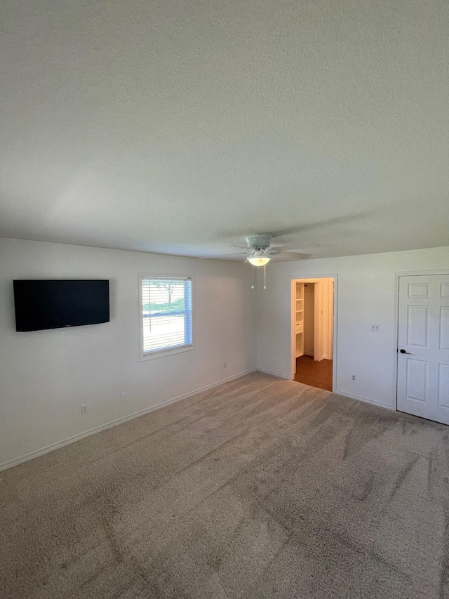 carpeted empty room with ceiling fan and a textured ceiling