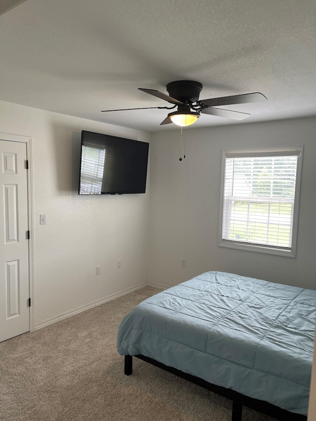 bedroom featuring ceiling fan, a textured ceiling, and carpet