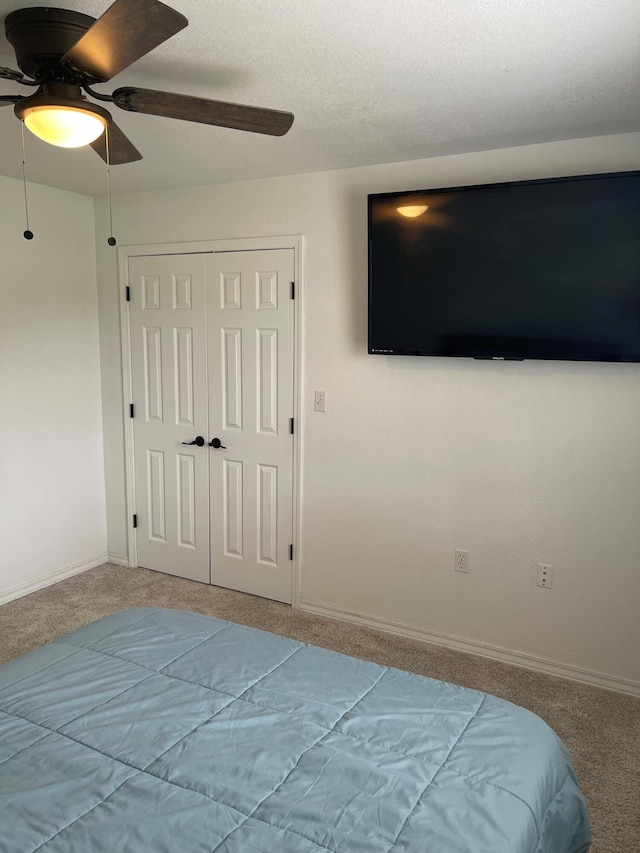 unfurnished bedroom featuring ceiling fan, a textured ceiling, a closet, and carpet