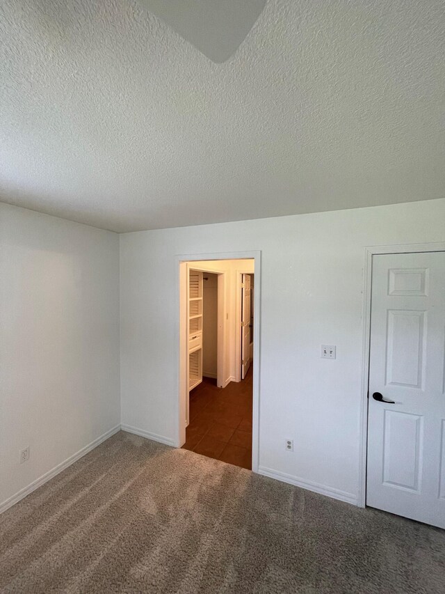 unfurnished room featuring dark carpet and a textured ceiling