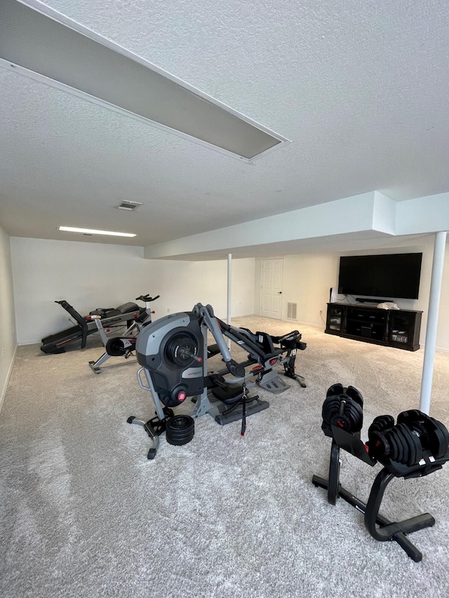 workout area with carpet floors and a textured ceiling