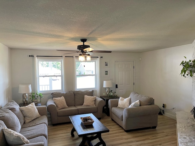 living room with a textured ceiling, light wood-type flooring, and ceiling fan