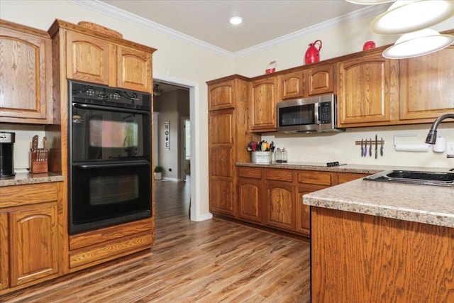 kitchen featuring wood-type flooring, ornamental molding, double oven, and sink