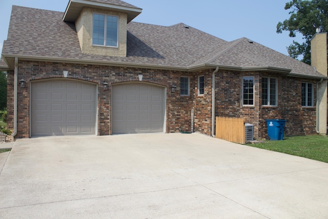 view of front of home featuring brick siding, an attached garage, driveway, and roof with shingles