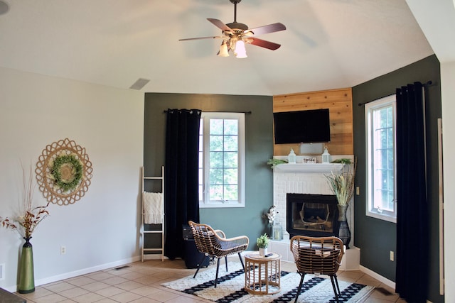 living area featuring light tile patterned flooring, vaulted ceiling, a fireplace, and ceiling fan