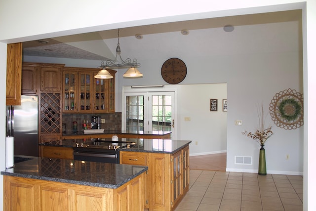 kitchen with stainless steel fridge, light tile patterned floors, black electric range oven, decorative light fixtures, and backsplash