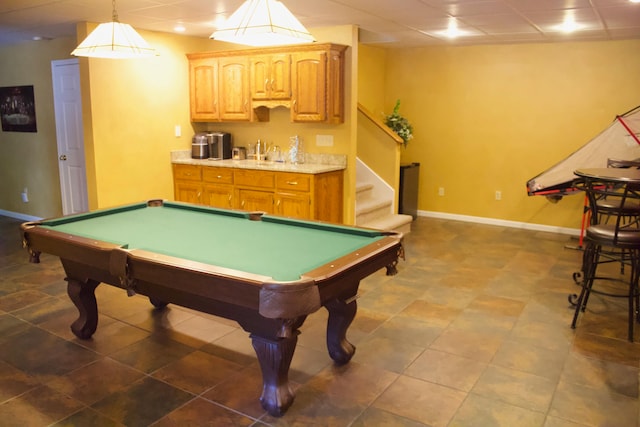 rec room with a paneled ceiling, dark tile patterned flooring, and sink