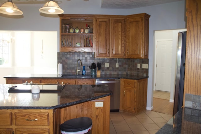 kitchen featuring backsplash, sink, dishwasher, hanging light fixtures, and light tile patterned floors