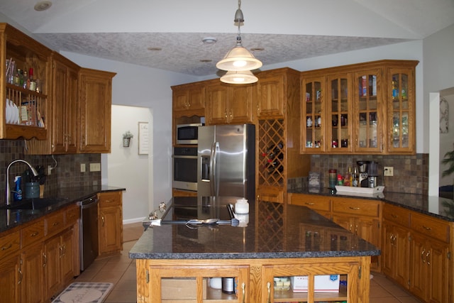 kitchen with tasteful backsplash, a sink, brown cabinets, light tile patterned flooring, and stainless steel appliances