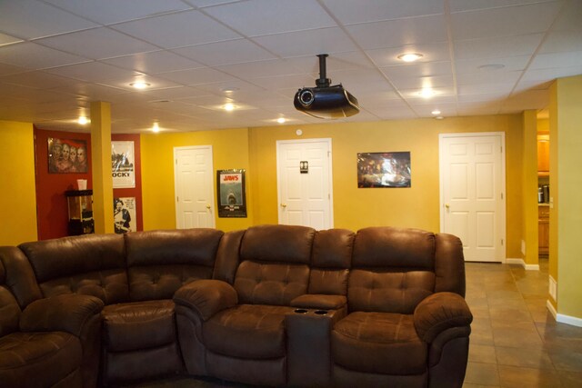 living room with baseboards, dark tile patterned floors, and a drop ceiling
