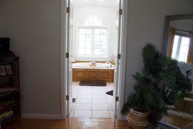 bathroom with wood finished floors, a garden tub, and baseboards
