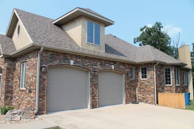 view of front of house with a chimney, driveway, a shingled roof, an attached garage, and brick siding