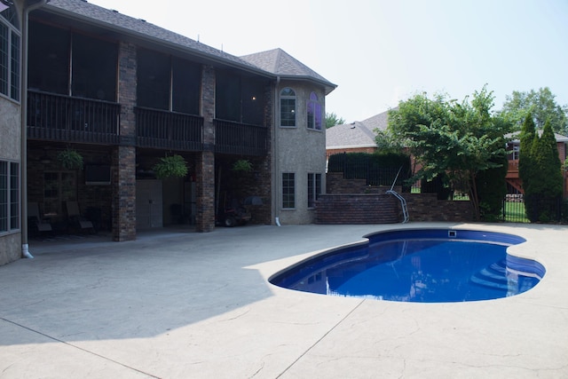 view of pool with a sunroom and a patio