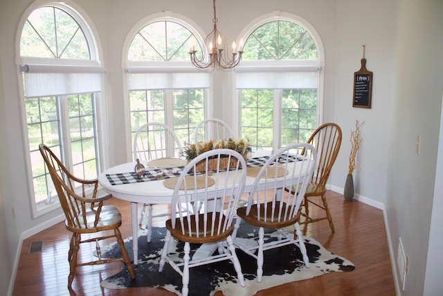 dining space with hardwood / wood-style floors, visible vents, a wealth of natural light, and a chandelier