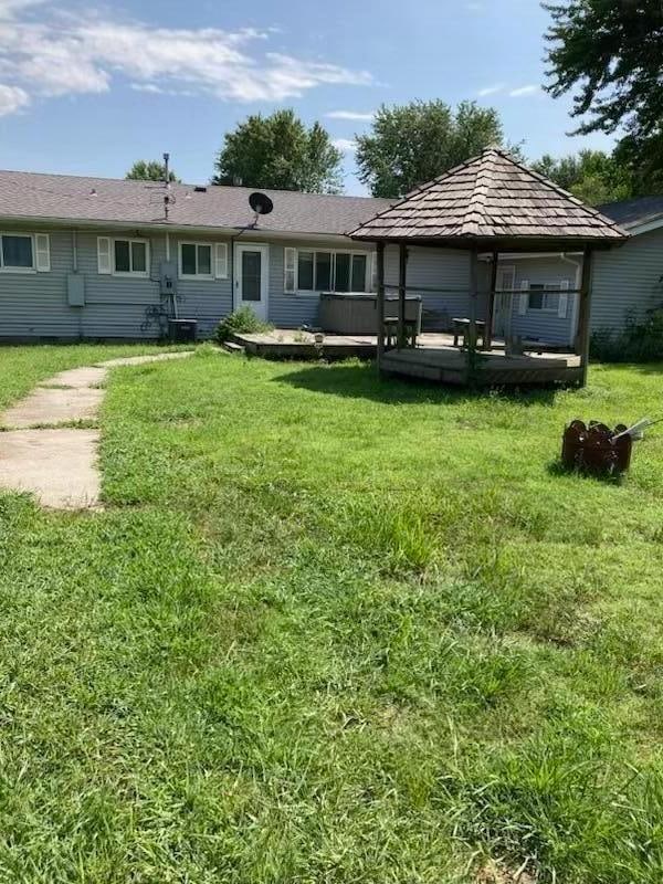 back of property featuring a deck and a lawn