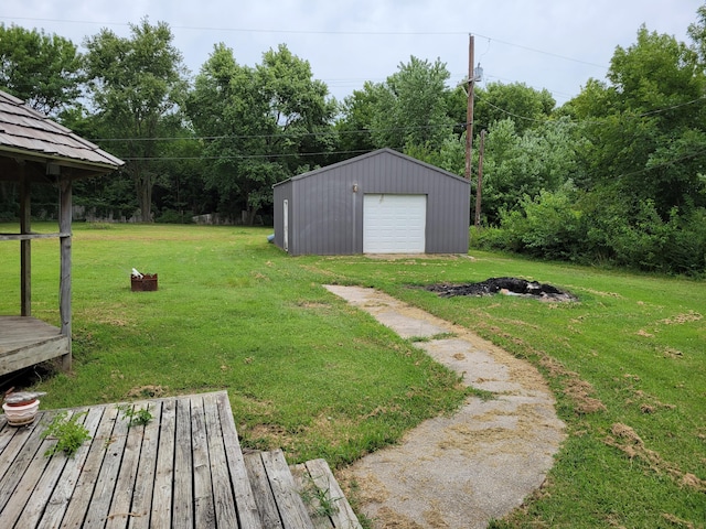 view of yard with a garage, an outbuilding, and a wooden deck