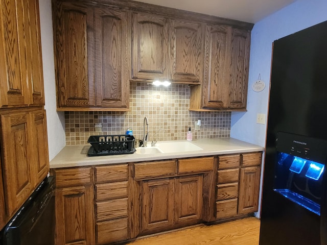 kitchen featuring black appliances, decorative backsplash, sink, and light hardwood / wood-style flooring