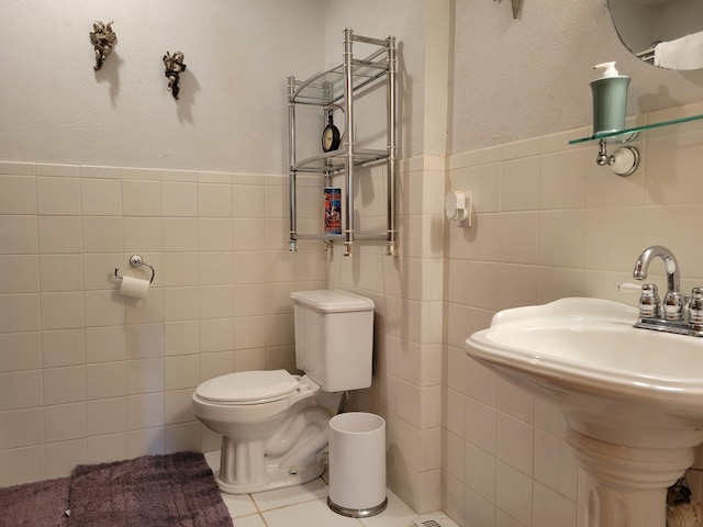 bathroom with tile patterned floors, tile walls, toilet, and sink