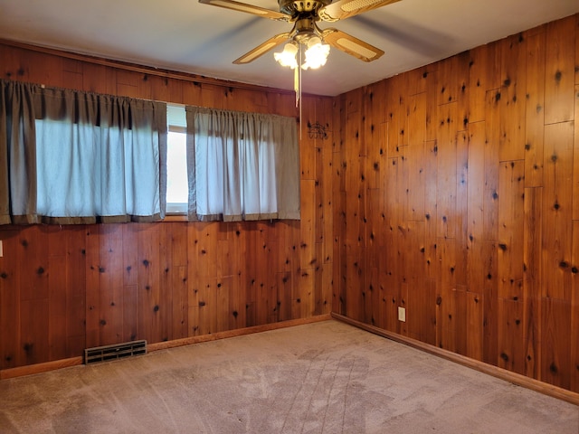 carpeted empty room with wooden walls and ceiling fan