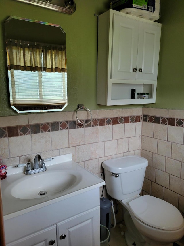 bathroom featuring vanity, tile walls, and toilet