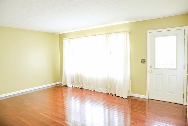 entrance foyer featuring wood-type flooring, a textured ceiling, and a wealth of natural light