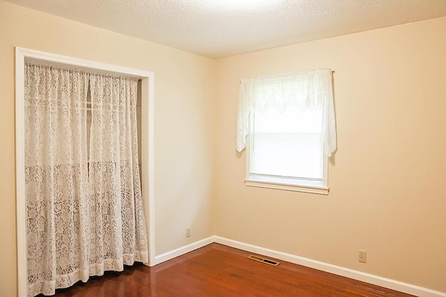 spare room with dark wood finished floors, baseboards, and visible vents