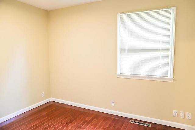 spare room featuring visible vents, baseboards, and dark wood-style floors