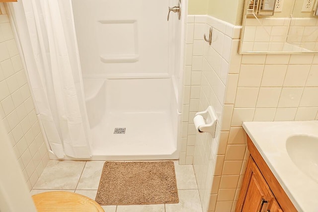 full bath with tile walls, vanity, tile patterned flooring, and a stall shower