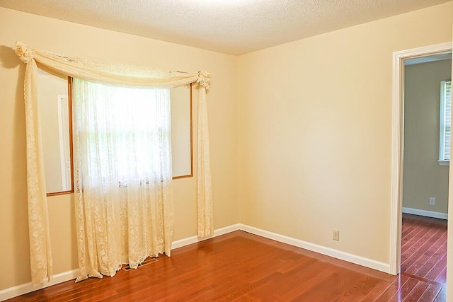 spare room with baseboards and wood finished floors