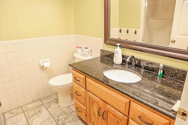 bathroom with wainscoting, vanity, tile walls, toilet, and tile patterned flooring