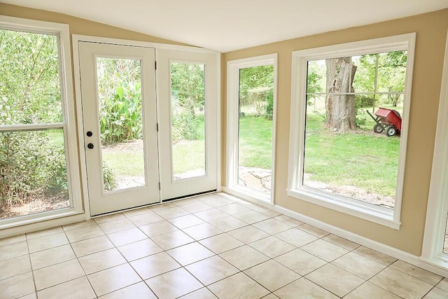 doorway with vaulted ceiling and light tile patterned floors