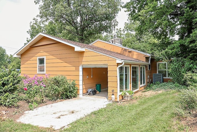 back of house with a lawn, driveway, a patio, and a garage