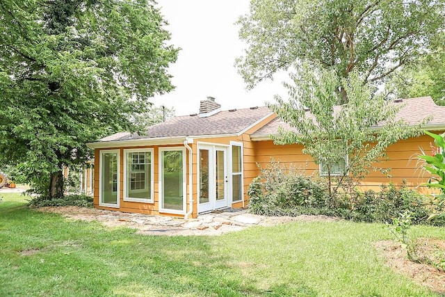 back of house featuring a lawn and a chimney