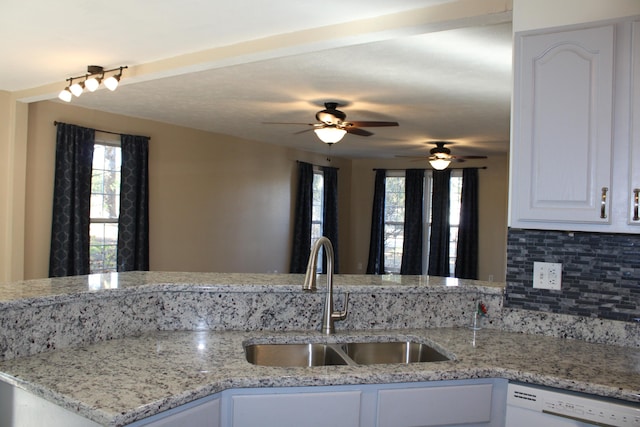 kitchen featuring white dishwasher, sink, white cabinets, light stone counters, and ceiling fan