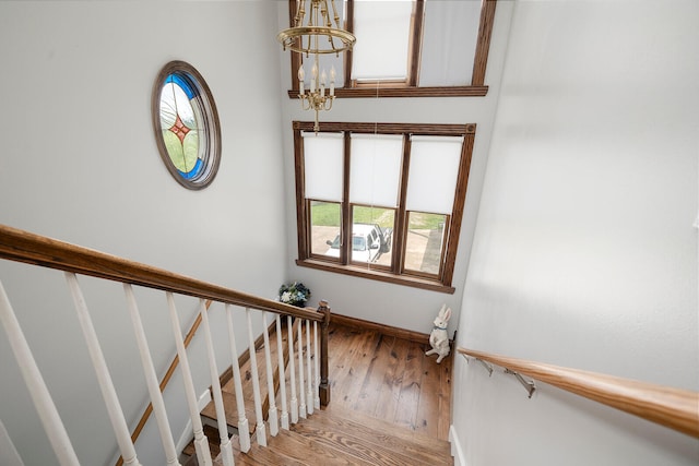 staircase with a notable chandelier and wood-type flooring