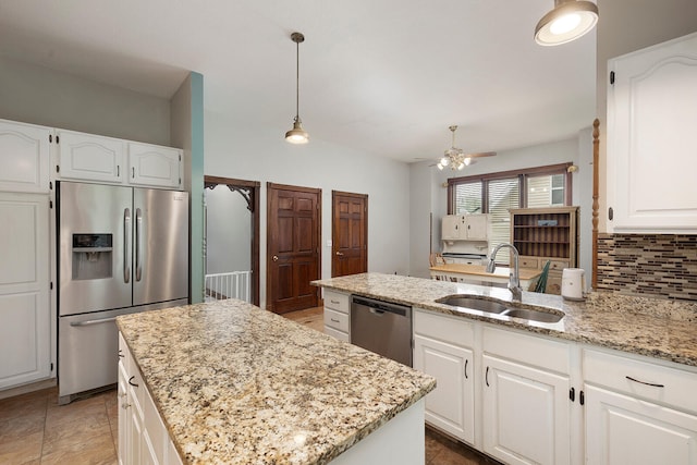 kitchen featuring a kitchen island, appliances with stainless steel finishes, white cabinetry, sink, and light stone countertops