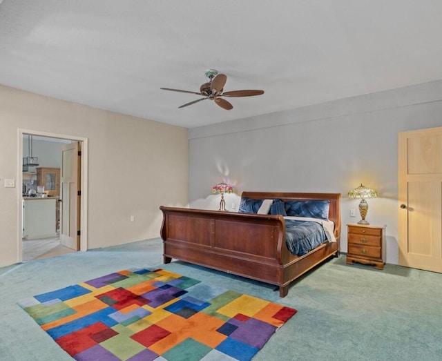 bedroom with ceiling fan, ensuite bath, and carpet flooring