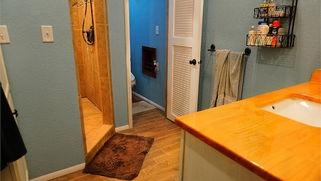 bathroom with wood-type flooring, a shower, vanity, and toilet