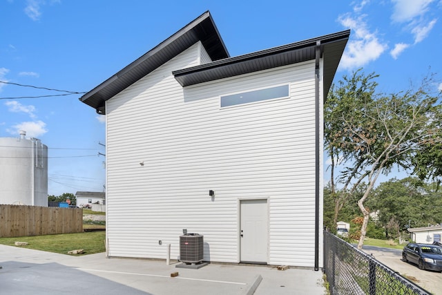 view of side of property featuring fence and central AC