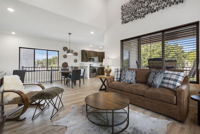 living area with a high ceiling, light wood-style flooring, and recessed lighting