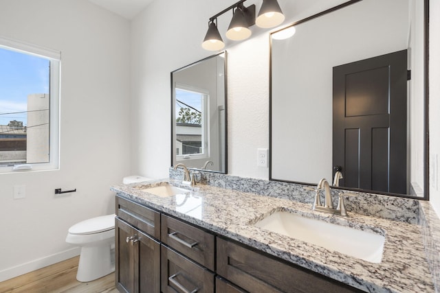 bathroom with toilet, baseboards, a sink, and wood finished floors