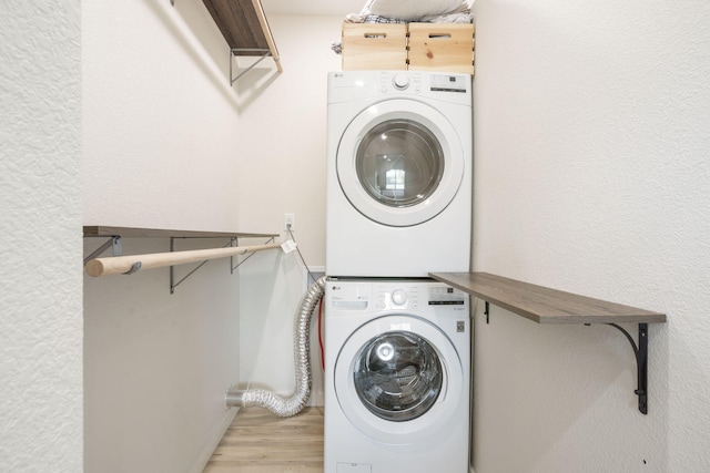 laundry area featuring laundry area, light wood finished floors, and stacked washer and clothes dryer