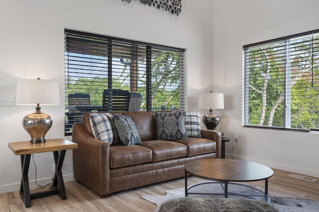 living area with light wood finished floors, visible vents, and baseboards