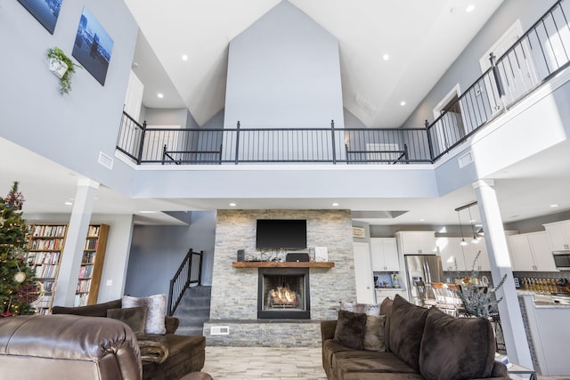 living room featuring ornate columns, a fireplace, and a towering ceiling