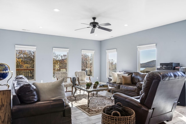 living room with light wood-type flooring, plenty of natural light, and ceiling fan