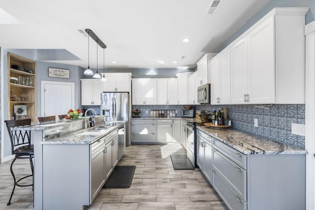 kitchen with sink, stainless steel appliances, pendant lighting, a breakfast bar, and white cabinets