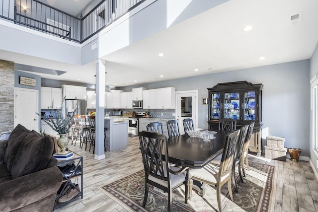 1379 Discovery Bay Dr, Shell Knob, MO 65747 - dining space with ornate columns, light wood-style flooring, a towering ceiling, and recessed lighting
