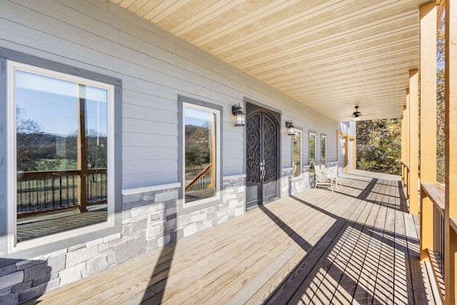 wooden terrace with ceiling fan and covered porch